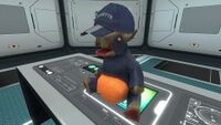 An Arcade Gorge Toy wearing a Cap and sitting on a Desk.