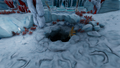 An opening in the ground that leads to a small dark cave