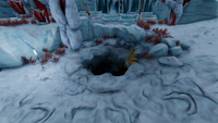 An opening in the ground that leads to a small dark cave